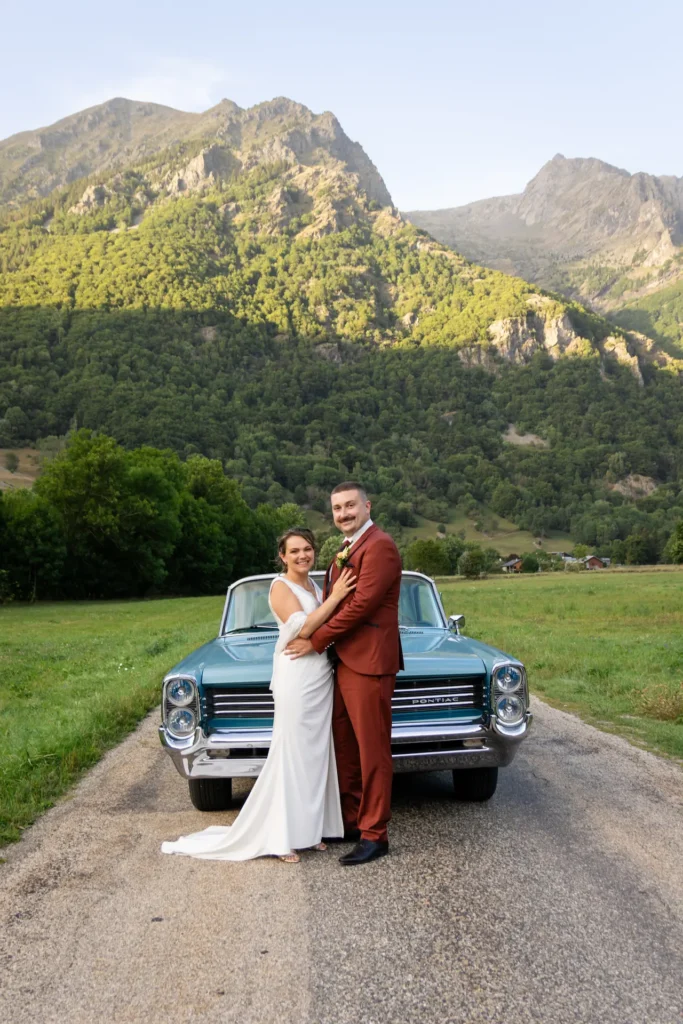 Photographe capturant un couple de mariés avec une Pontiac vintage en montagne