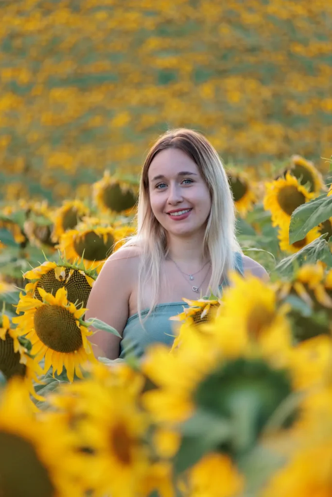 Une jeune fille sourit dans un champ de tournesols dorés en Isère